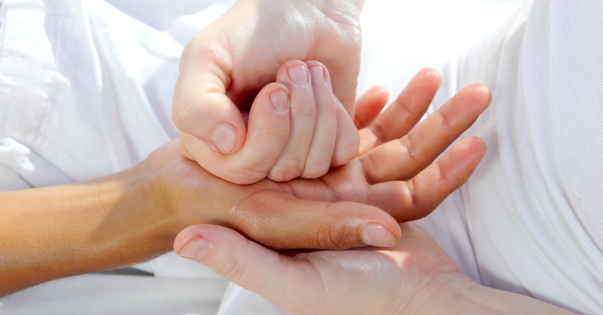 A practitioner massaging a patient's hand.